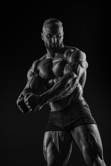 Silhouette of a strong bodybuilder. Confident young fitness athlete with a powerful body and perfect abs. Black and white photography. Dramatic light. Mixed media