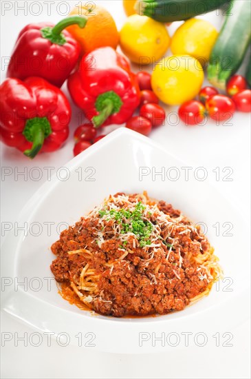 Italian classic spaghetti with bolognese sauce and fresh vegetables on background