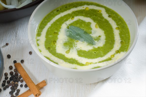 Fresh spinach soup on a white bowl with sage and cream on top