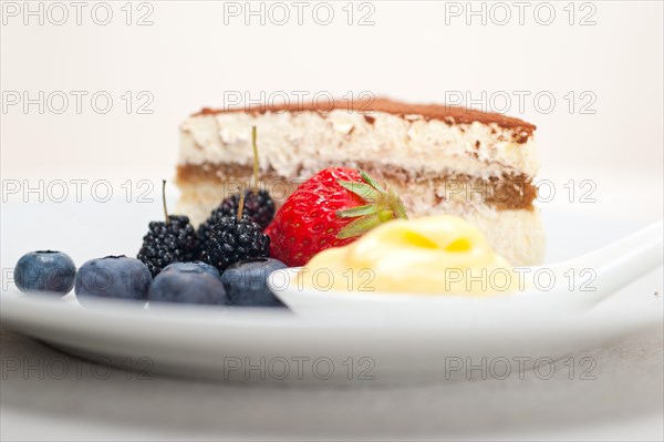 Classic Italian tiramisu dessert with berries and custartd pastry cream on side