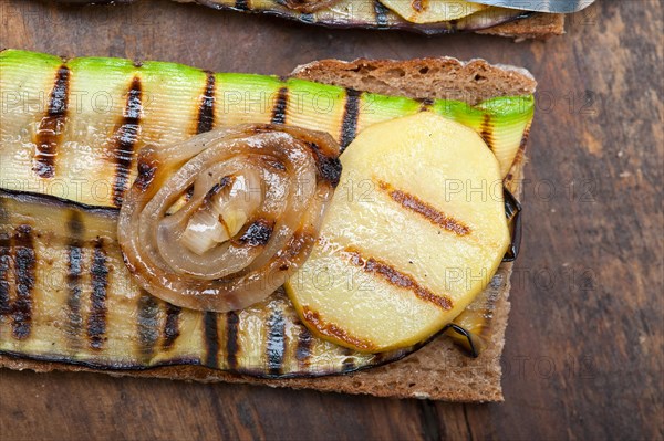 Grilled vegetables on rustic bread over wood table