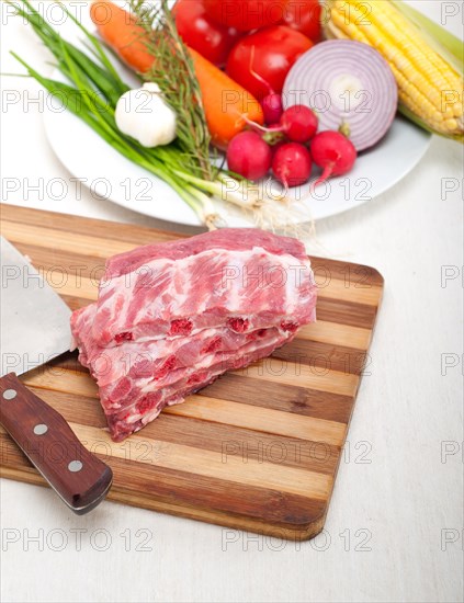 Chopping fresh pork ribs with vegetables and herbs ready to cook