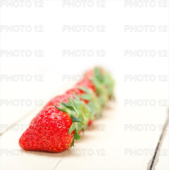 Fresh organic strawberry over white rustic wood table