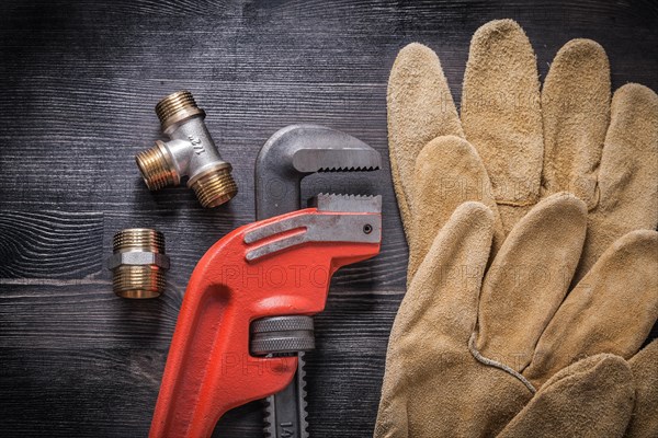 Adjustable wrench plumbing fittings protective gloves on wooden board