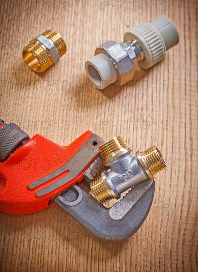 Close-up of pipe fasteners and spanner on wooden board