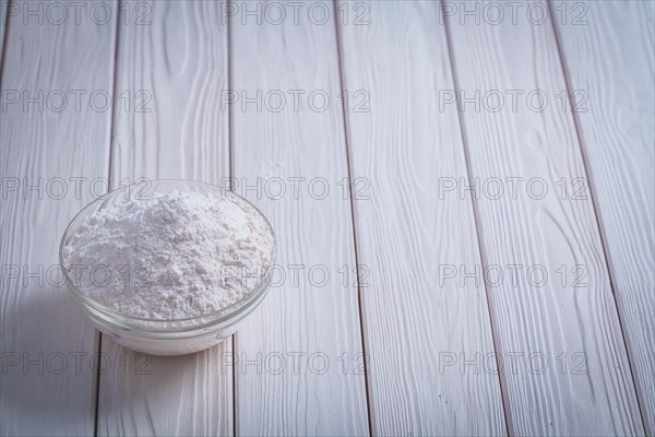 Bowl with white natural flour on white lacquered old wooden board Food and drink concept