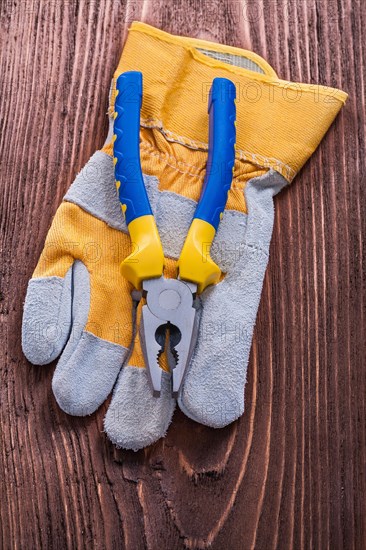 Plastic tongs with construction glove on wooden plate Maintenance concept