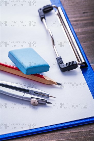 Eraser pencil compass clipboard on vintage wooden board learning concept