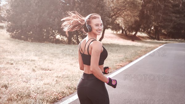 Fitness girl in sportswear runs through the evening sunny park. Healthy lifestyle. Mixed media