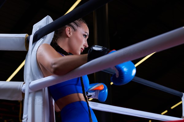 Powerful charged girl stands in the corner of the ring and is ready to explode in the next round. The concept of wrestling and boxing. Mixed media