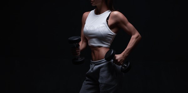 Athletic fitness woman posing in the studio on a dark background. Photo of an attractive woman in fashionable sportswear. Sports and healthy lifestyle. Mixed media