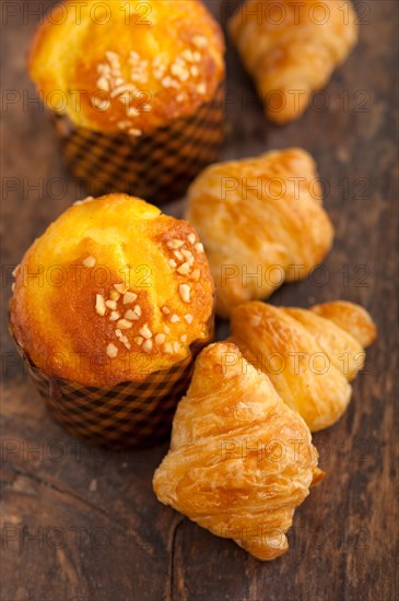 Fresh baked muffin and croissant mignon on old wood table