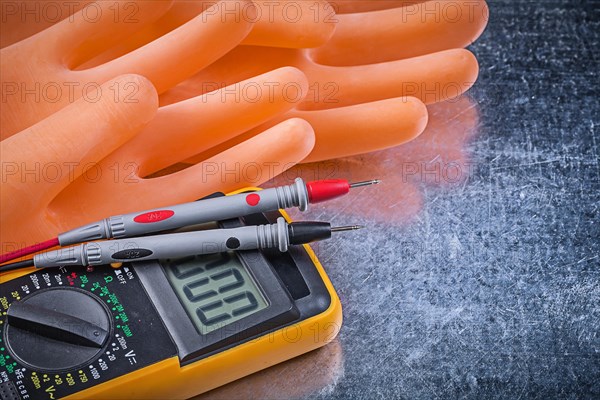 Digital electrical tester insulating rubber gloves on metallic background