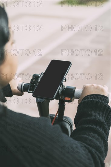 Over-the-shoulder view of a woman on a bicycle using a smartphone mounted on the handlebar