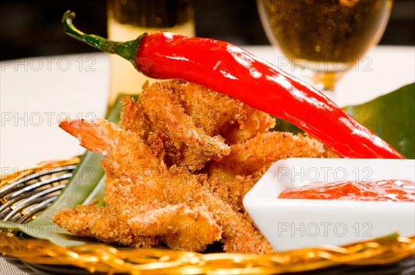 Fresh deep fried buffalo shrimps with a red chili pepper on top and sweet and sour sauce dip on side