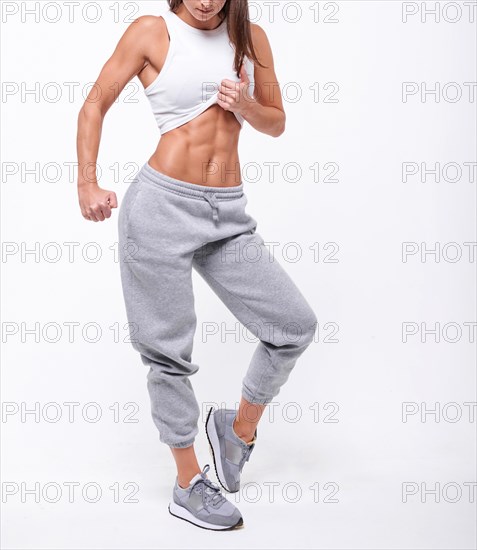 No name portrait. Young white fitness woman wearing sportswear standing over white wall background. Fitness concept. Mixed media