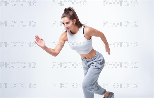 Sports woman runner on a white background. Photo of an attractive woman in fashionable sportswear. Dynamic movement. Side view. Sports and healthy lifestyle. Mixed media