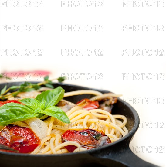 Italian spaghetti pasta with baked tomatoes basil and thyme sauce on a cast iron skillet