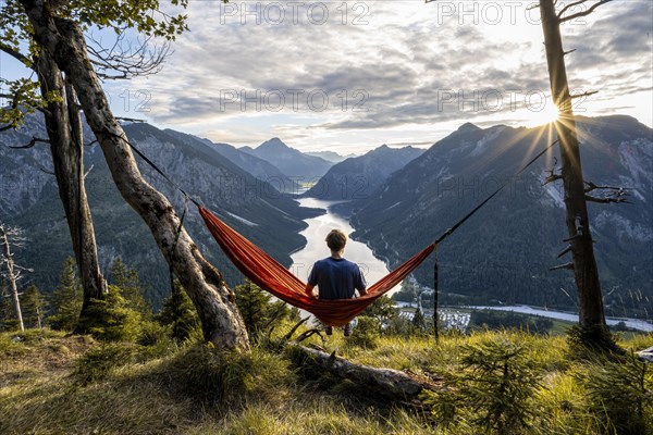 Young man sitting in an orange hammock