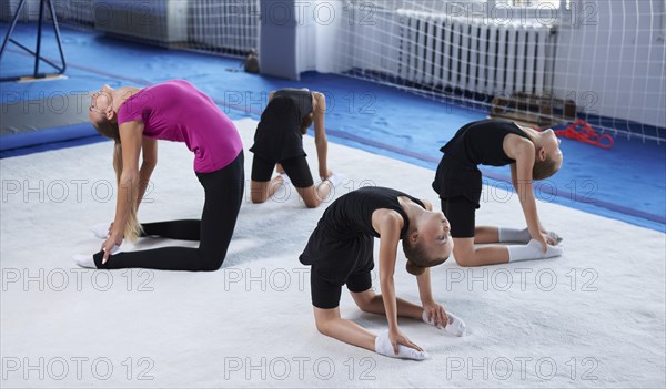 Training in the gym class. A group of children under the guidance of a coach perform exercises. Gymnastics concept. Mixed media