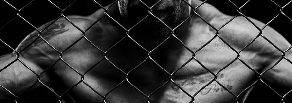 Black and white image of a man in a boxing cage. The concept of sports