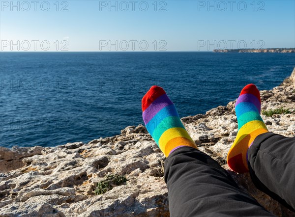 Socks with the colors of the flag of the LGBTQ community. relaxed in front of the sea. Pride concept with copy space