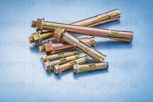 Group of metal anchor bolts with construction nuts on metallic background repairing concept