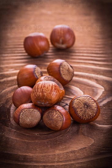 Small pile of hazelnuts on an old wooden board Food and drink Still life