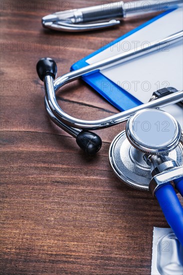 Stethoscope clipboard biros on vintage wooden board wery close-up view medical comcept