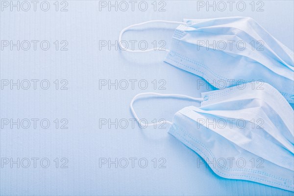 Two disposable face masks on a blue background with spaces