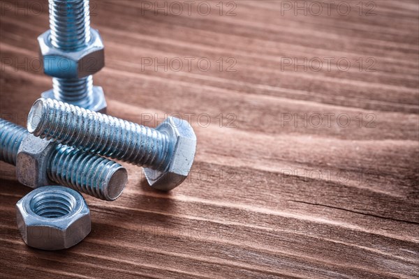 Collection of metal bolts and nuts on vintage wooden board Building concept