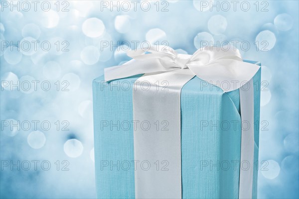 Close up view blue gift box with white bow on blurred background