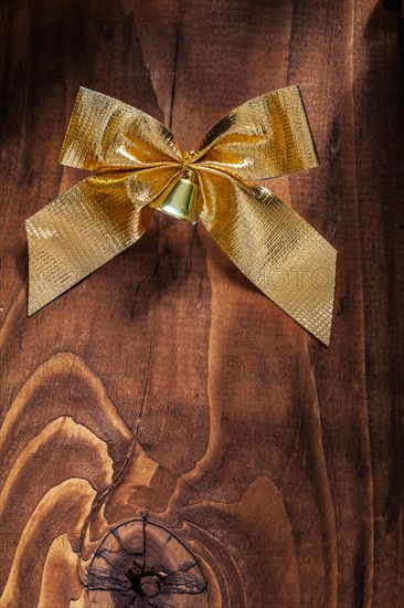 Golden bow with bells on an old wooden board