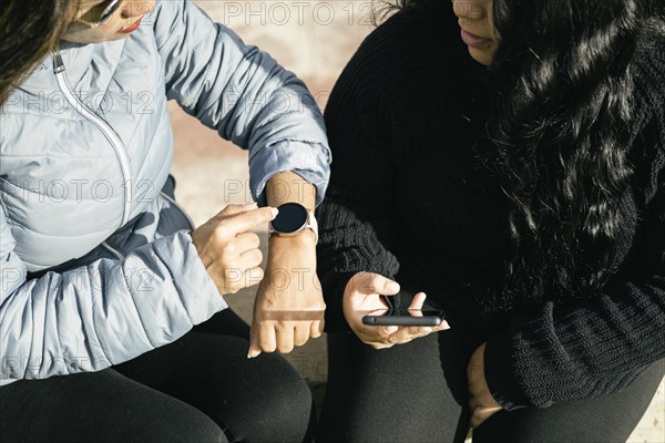 Two young beautiful female friends with smart devices texting and chatting having fun on social media