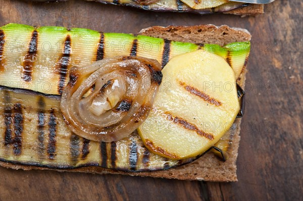 Grilled vegetables on rustic bread over wood table