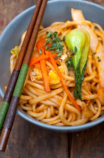 Hand pulled stretched Chinese ramen noodles on a bowl with chopstick