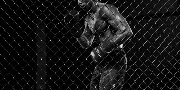 Black and white image of a man in a boxing cage. The concept of sports