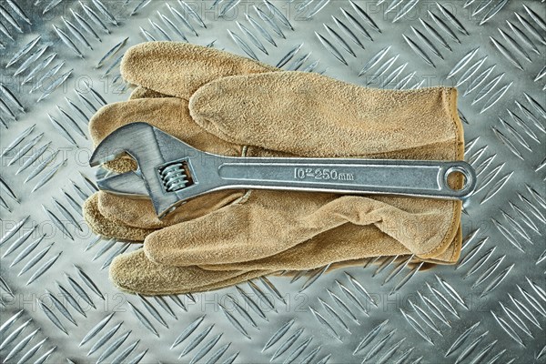 Adjustable spanner protective gloves on corrugated metal background