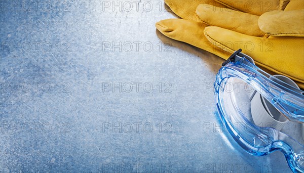Assortment of safety goggles gloves on metallic background construction concept