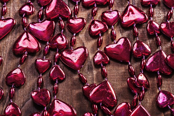 Background red valentines beads garland on old wooden board horizontal version