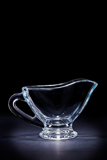 Transparent glass sauce boat on a black background