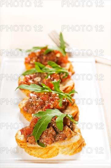 Fresh tipycal italian bruschetta with tomato and arugula on top