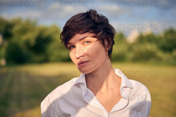 Retro portrait of a stylish beautiful woman in a white shirt on the background of a sunny meadow. The concept of style and fashion
