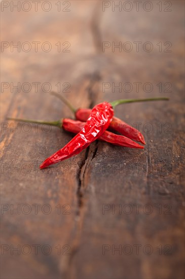 Dry red chili peppers over old wood table