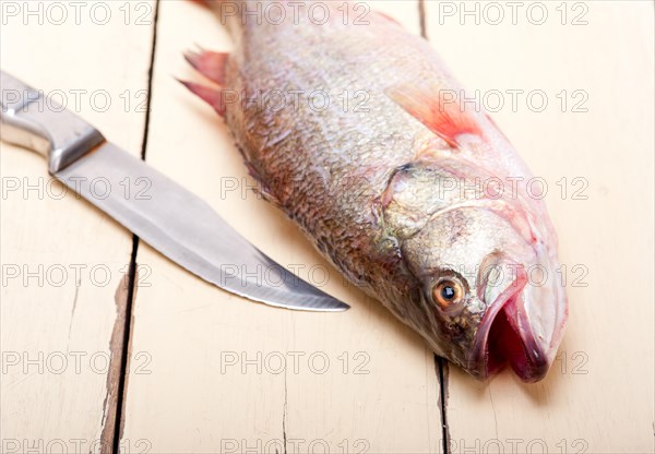 Fresh whole raw fish on a wooden table ready to cook