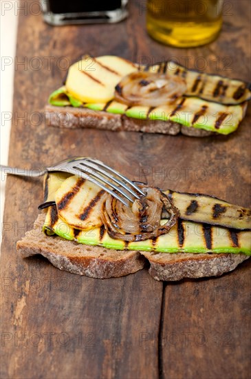 Grilled vegetables on rustic bread over wood table