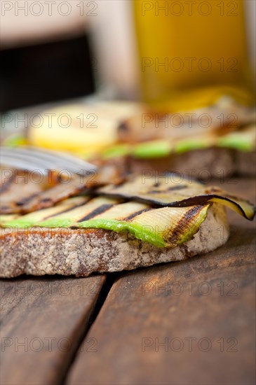 Grilled vegetables on rustic bread over wood table