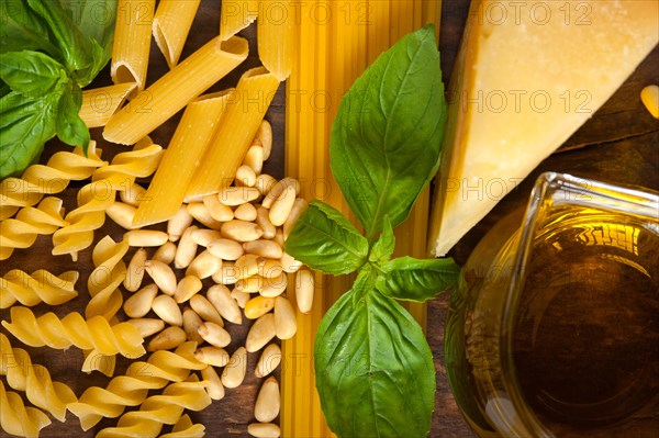 Italian basil pesto ingredients and raw pasta over old wood macro