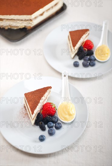 Classic Italian tiramisu dessert with berries and custartd pastry cream on side