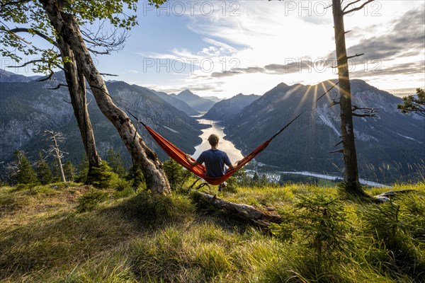 Young man sitting in an orange hammock